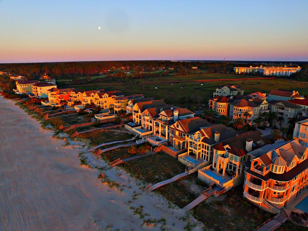 Stunning aerial shot of luxurious beachfront homes on Hilton Head Island at sunset, showcasing coastal beauty.