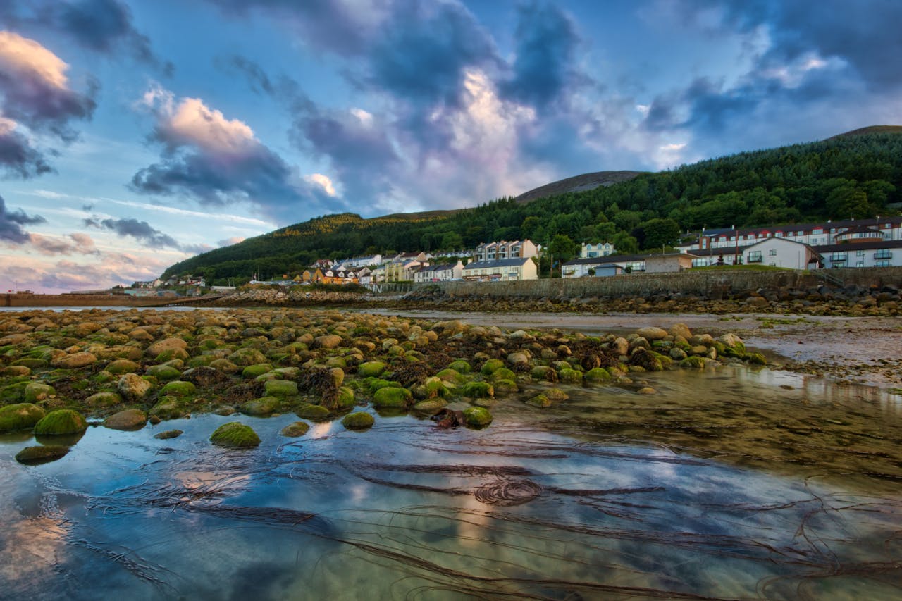 Idyllic view of a coastal village with mossy rocks and mountains in Northern Ireland.